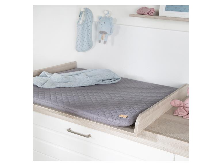 Table à langer avec matelas gris, couverture bleue et jouets