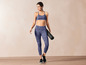 Une femme portant un soutien-gorge de sport bleu et un legging avec un tapis de yoga.