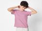 Femme portant un t-shirt rose et un pantalon blanc.