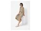 Une femme portant une robe beige avec une ceinture et des baskets blanches.