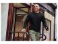 Un homme en sweat-shirt noir et pantalon cargo vert monte les escaliers.