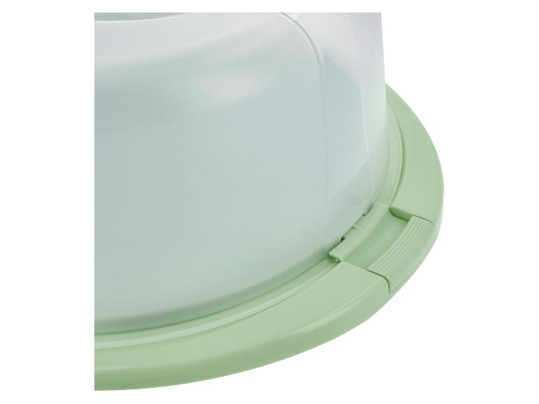 Gros plan d'un porte-gâteau vert clair avec un couvercle dôme transparent.