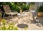 Mobilier de jardin: deux chaises et une table avec des boissons sur un patio ensoleillé.