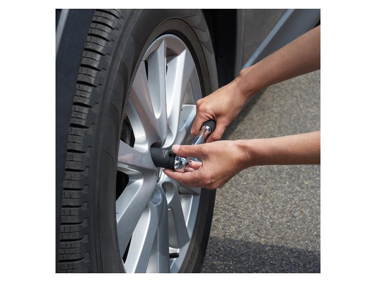 Une personne utilise une clé à douille pour serrer un écrou de roue sur une voiture