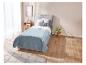 Couette matelassée bleu clair sur lit avec coussin et tapis.