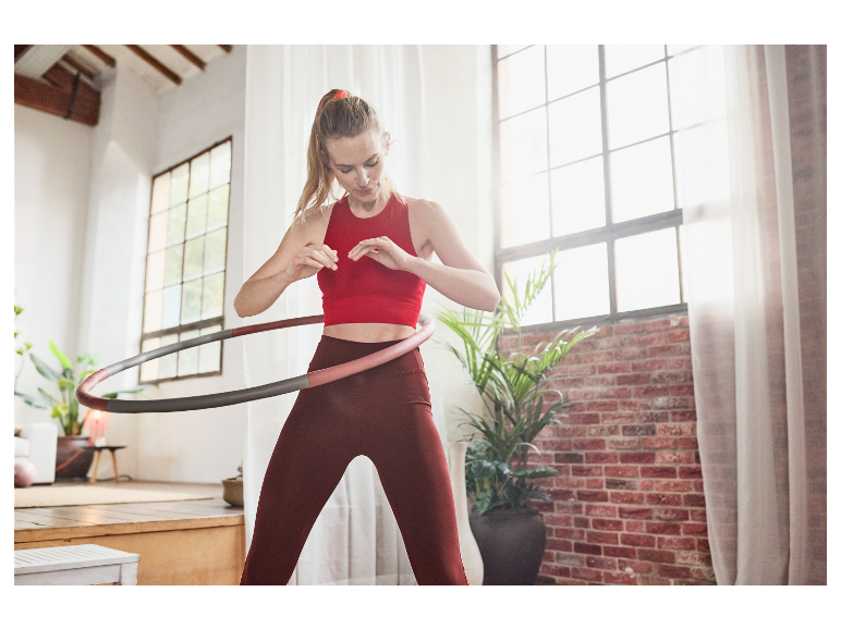 Femme faisant du sport à la maison avec un hula hoop.
