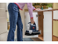 Une personne range un nettoyeur de tapis portable dans une armoire.