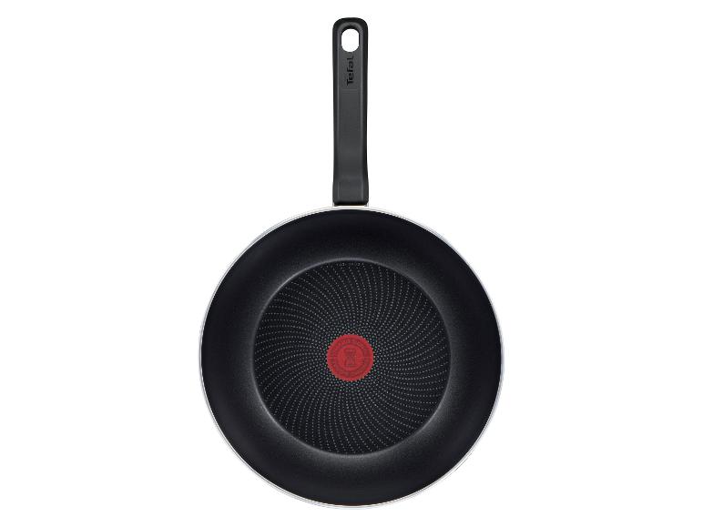 Poêle à frire noire avec une poignée et un indicateur de température rouge au centre.