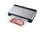 Machine de mise sous vide argentée avec un morceau de viande emballé.