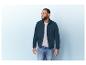 Un homme porte une veste en polaire vert foncé et un jean bleu.