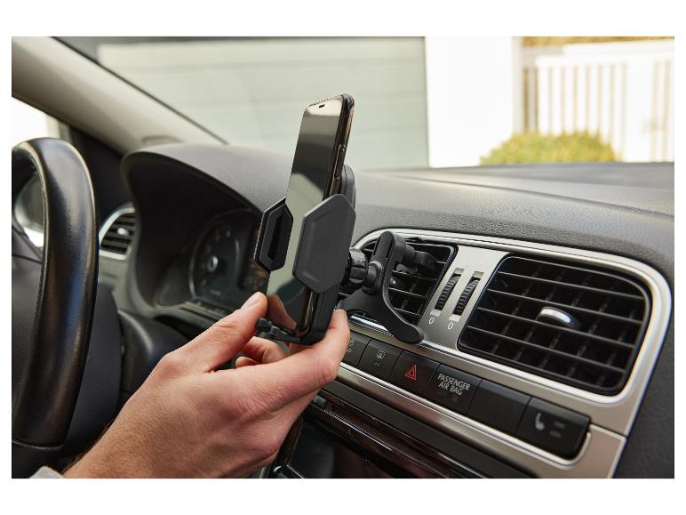 Des mains installent un support de téléphone portable pour voiture dans une grille d'aération.