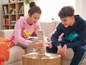 Deux enfants jouent à un jeu de blocs sur une table basse.