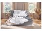 Chambre à coucher avec lit gris, couettes et oreillers blancs, rideaux beiges et parquet.