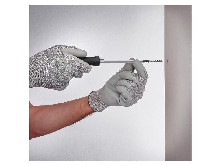 Gants de travail et tournevis fixant une vis dans un mur.