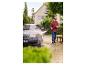 Homme lavant une voiture avec un nettoyeur haute pression devant une maison.