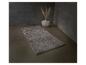 Tapis de bain gris sur sol en béton avec vase et herbe de la pampa.