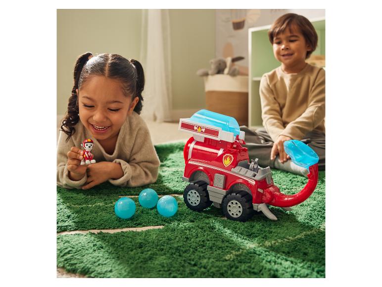 Deux enfants jouent avec un véhicule et une figurine Pat' Patrouille sur un tapis vert.
