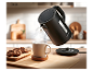 Une bouilloire électrique Silvercrest noire verse de l'eau dans une tasse sur une surface en bois.