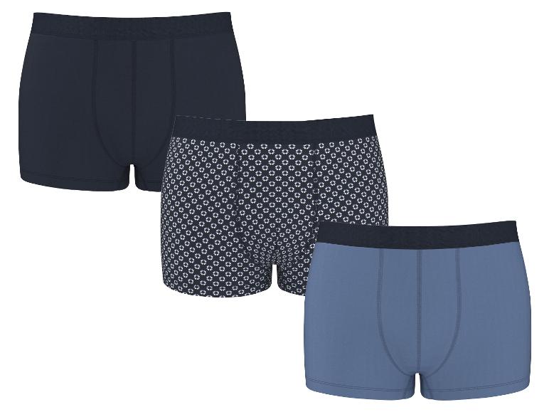 Lot de trois boxers en coton pour homme: un bleu marine, un à motif géométrique et un bleu clair.