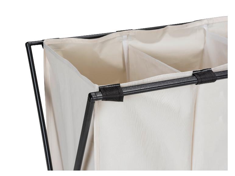 Gros plan sur un panier à linge en tissu beige à trois compartiments avec une structure métallique noire.