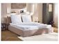 Lit avec matelas, oreillers et surmatelas blancs dans une chambre moderne.
