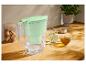 Carafe filtrante à eau vert menthe sur une table en bois, avec des verres et du thé.