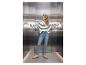 Femme en jean et pull rayé debout dans un ascenseur, mains sur les murs.