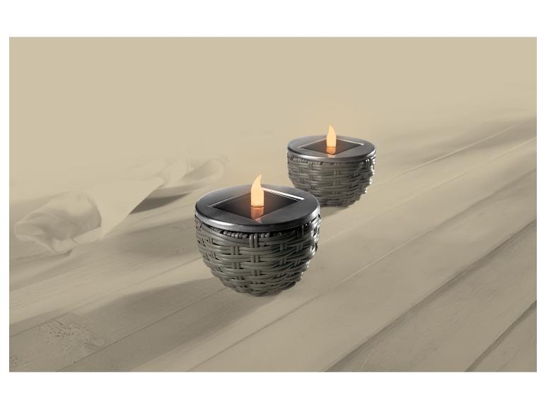 Deux lampes solaires à effet flamme sur une table en bois avec nappe blanche.