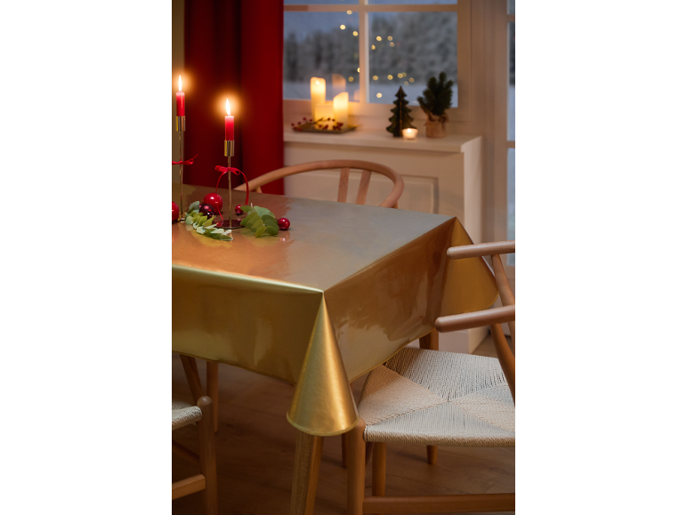 Table de salle à manger festive avec nappe dorée, bougies rouges et décorations de Noël.