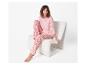 Pyjama rose femme à motif cœurs, assise dans un fauteuil blanc.