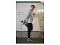 Homme en sweat-shirt gris et pantalon noir s'étirant près d'un mur carrelé.
