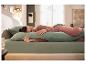 Une femme dort confortablement dans son lit, serrant un long oreiller de corps vert LIVARNO.