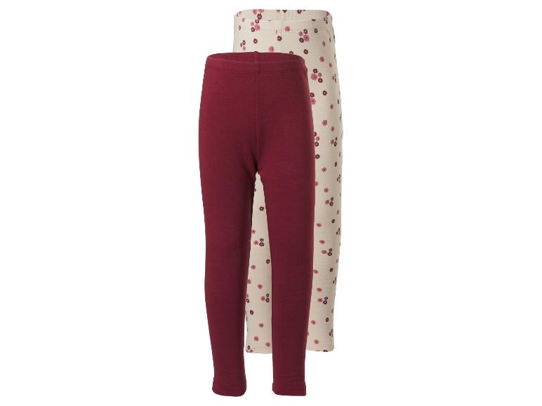 Deux leggings bébé: un bordeaux uni et un crème à motif floral.