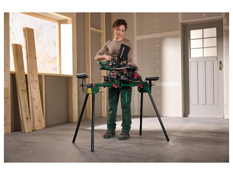 Femme préparant une scie à onglet sur un support dans une pièce avec des planches de bois.