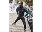 Un homme en veste noire et pantalon de jogging, avec des chaussures de sport bleues