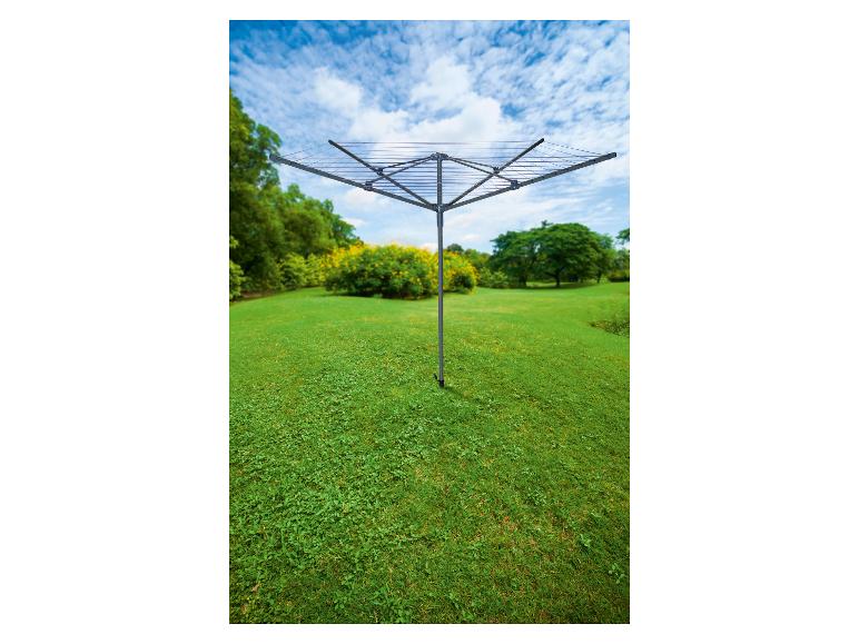 Séchoir à linge à quatre bras sur une pelouse verte avec des arbres et des fleurs en arrière-plan
