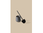Brosse de toilette noire avec support en céramique sur fond beige.