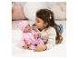 Fille jouant avec une poupée bébé vêtue de rose, allongée sur un tapis blanc.