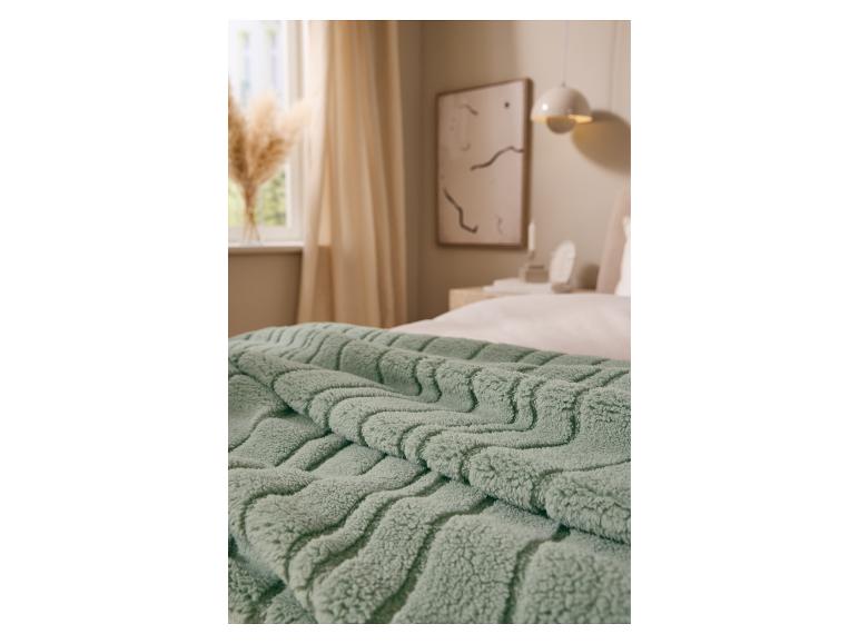Doux plaid vert LIVARNO home posé sur un lit.