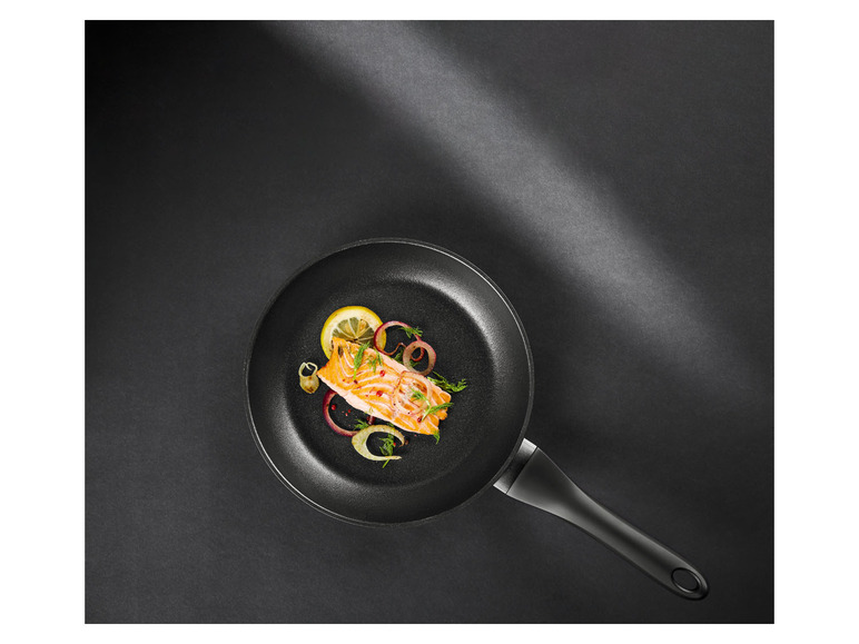 Un filet de saumon frit dans une poêle noire.