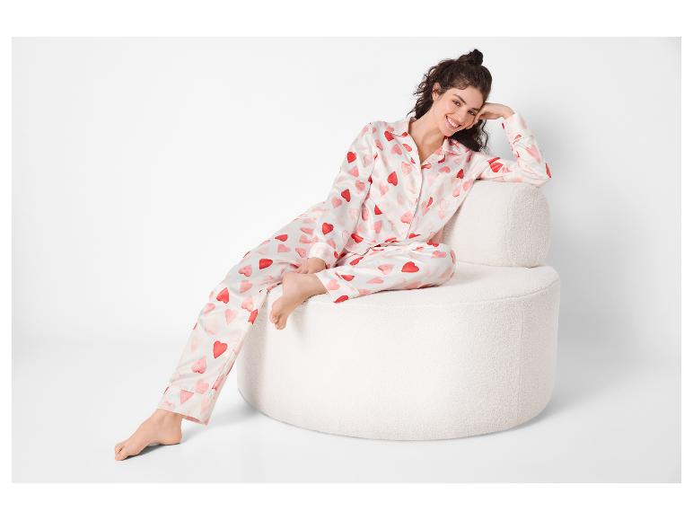 Femme en pyjama blanc à cœurs rouges, assise sur un fauteuil blanc.