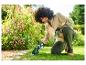 Une femme utilise une tondeuse à gazon Parkside pour entretenir son jardin fleuri.