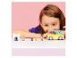 Fille jouant avec une camionnette jouet jaune et de petites figurines sur une table.