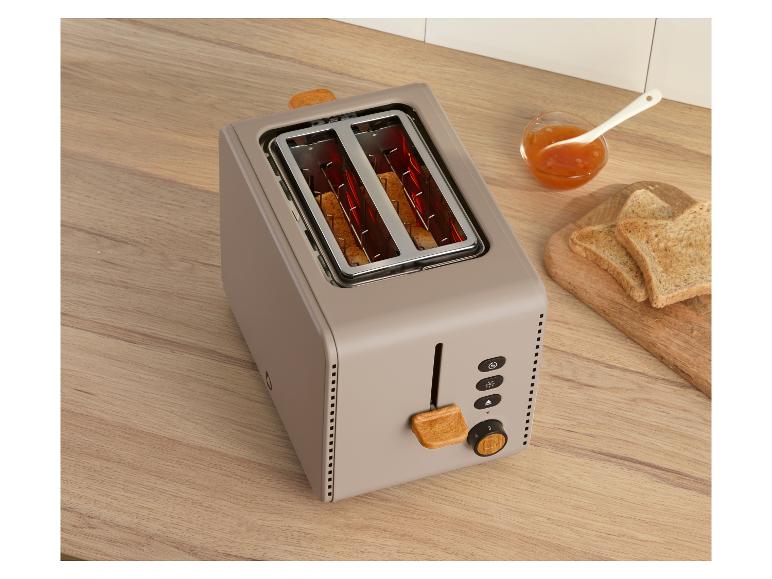 Grille-pain beige avec accents bois, toasts et confiture sur un comptoir en bois.