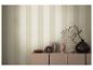Papier peint rayé beige et crème, avec des objets décoratifs sur un meuble.