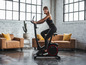 Une femme sur un vélo d'appartement noir dans un salon moderne.