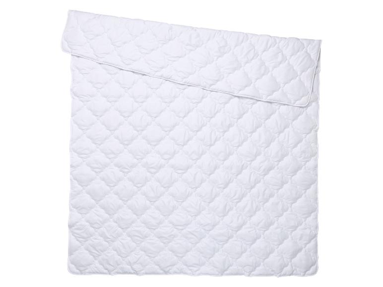 Couette blanche matelassée, pliée, avec un motif en losanges.