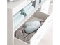 Commode blanche avec des étagères ouvertes et des tiroirs, remplie de vêtements pour bébé et d'un nuage en peluche.