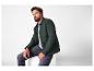 Un homme portant une veste vert foncé et un jean gris.