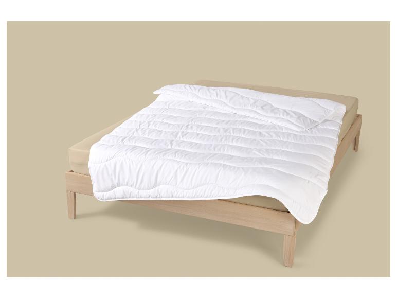 Couette blanche sur un lit en bois avec des draps beiges